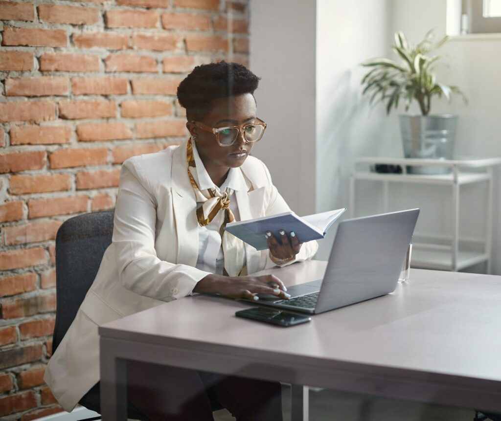 Black businesswoman working on laptop at corporate office.